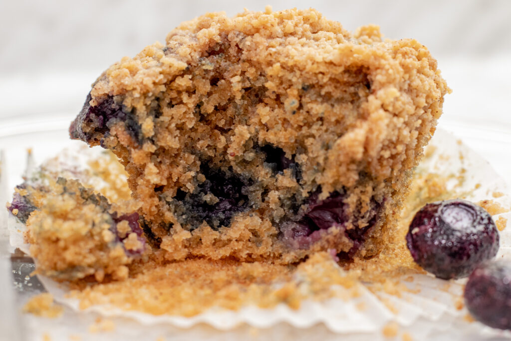 Best blueberry buttermilk muffin with streusel top single muffin close-up with bite removed